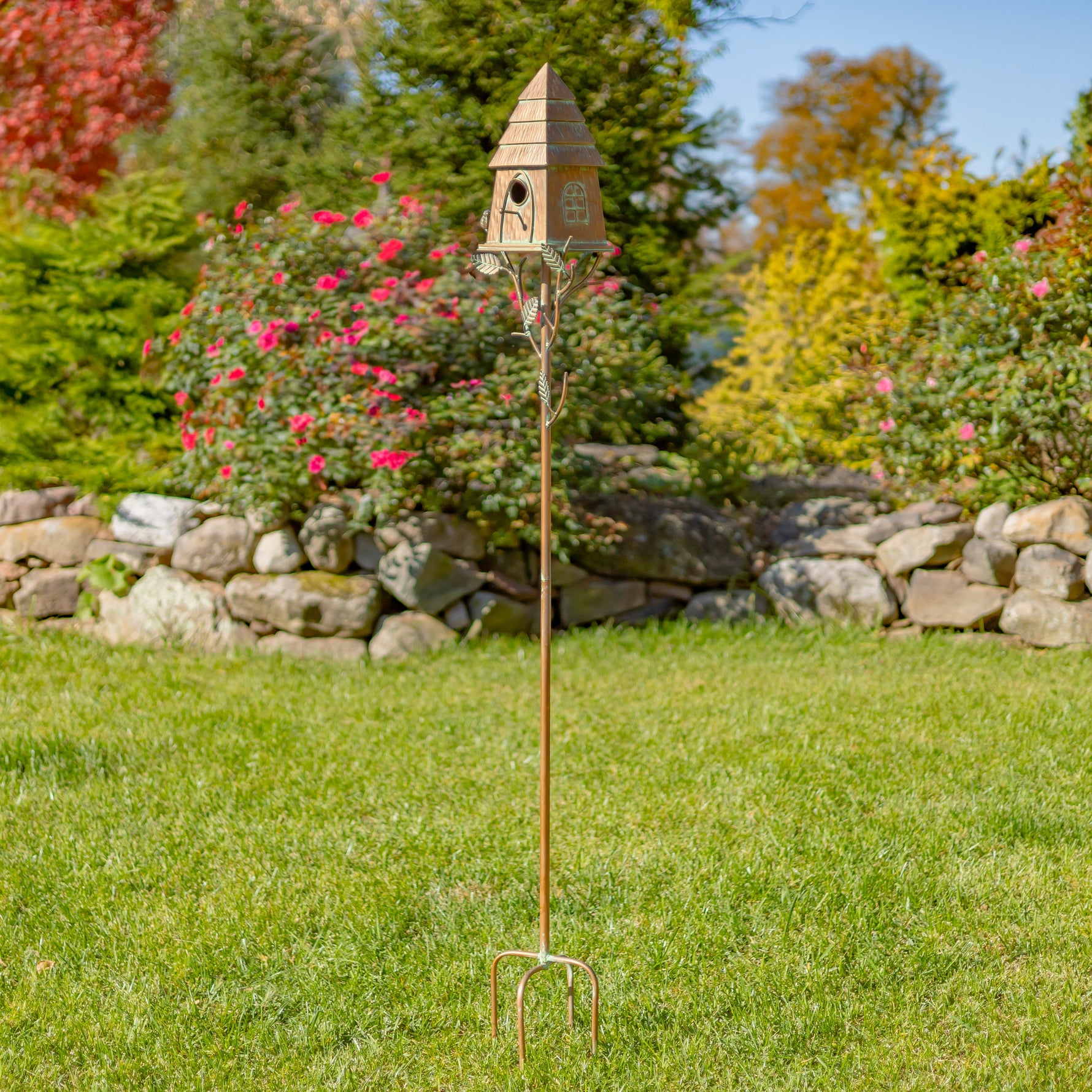 Decorative garden tool with birdhouse design on a grassy lawn