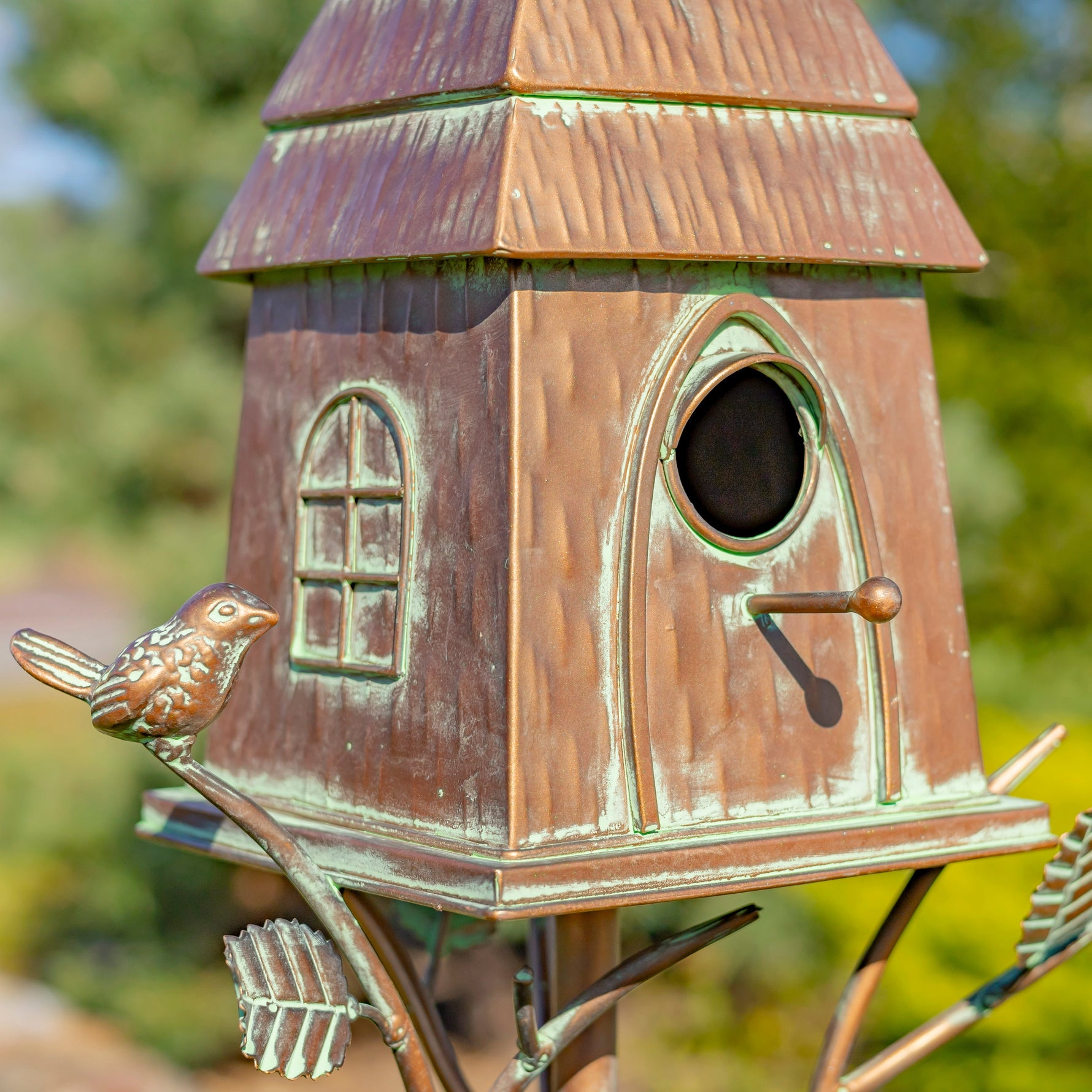 Copper birdhouse with decorative elements on a blurred natural background