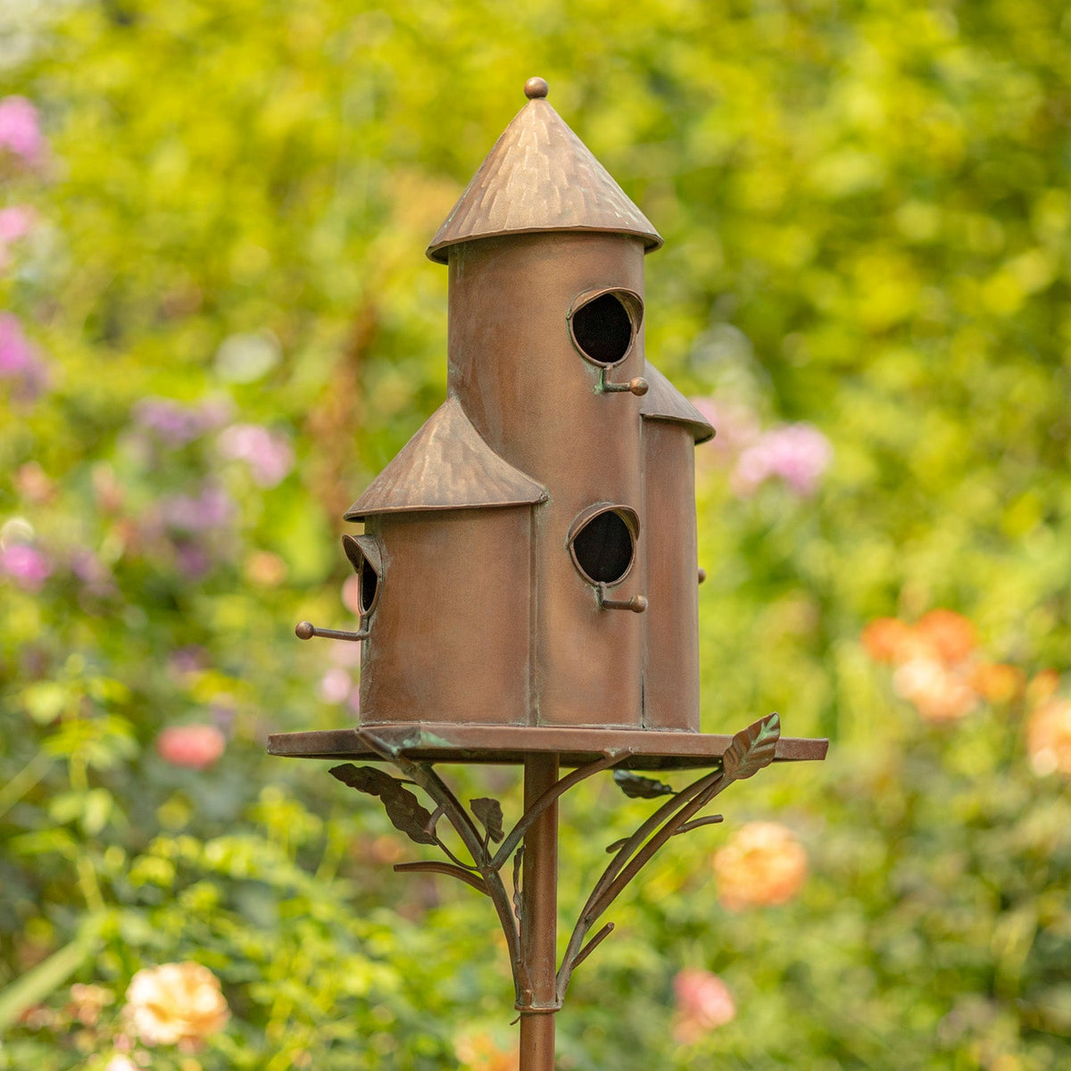 Decorative birdhouse on a stand with a blurred garden background