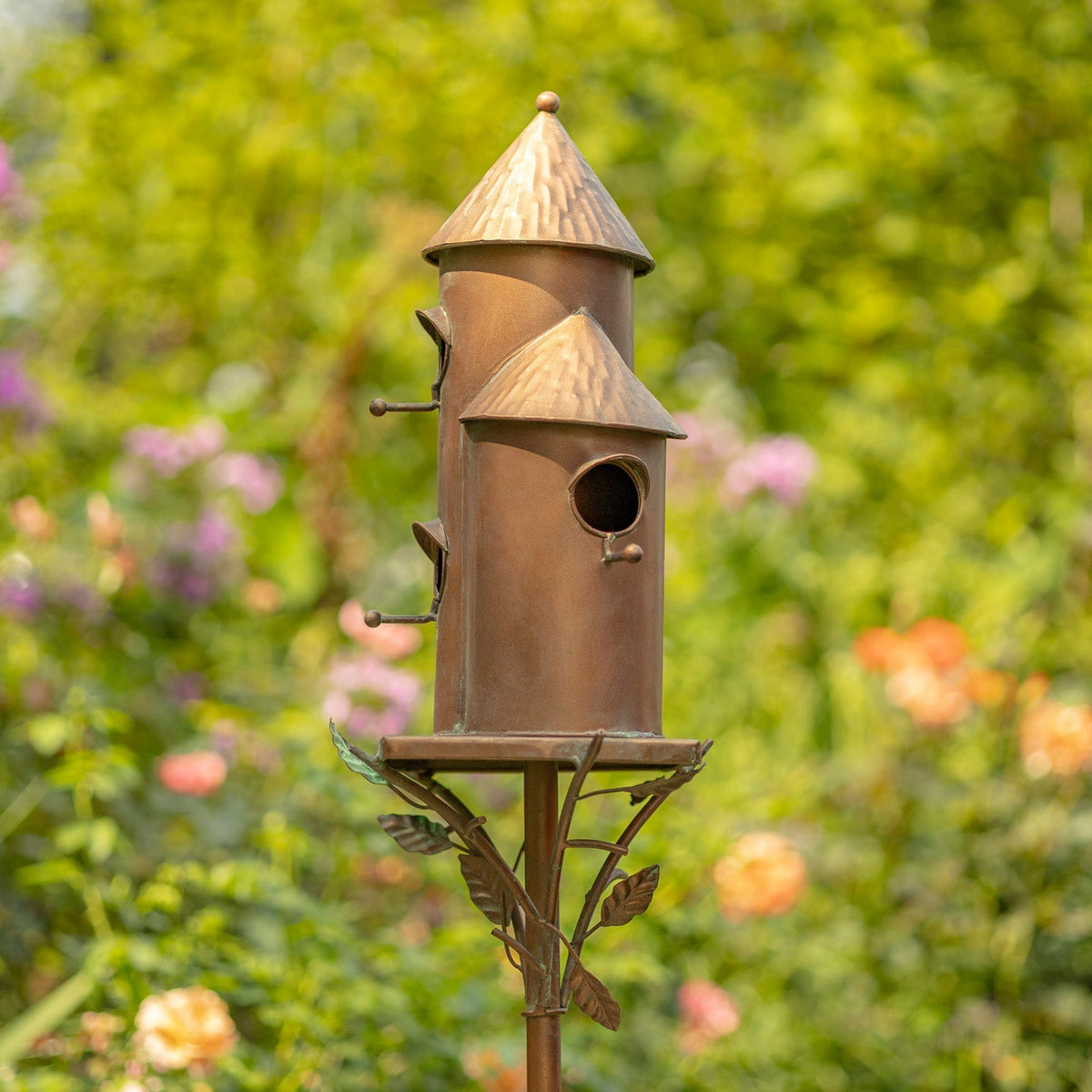 Decorative birdhouse on a stand with a garden background