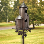 Metal birdhouse on a stand with a blurred green outdoor background