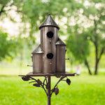 Decorative birdhouse on a stand with a blurred green garden background