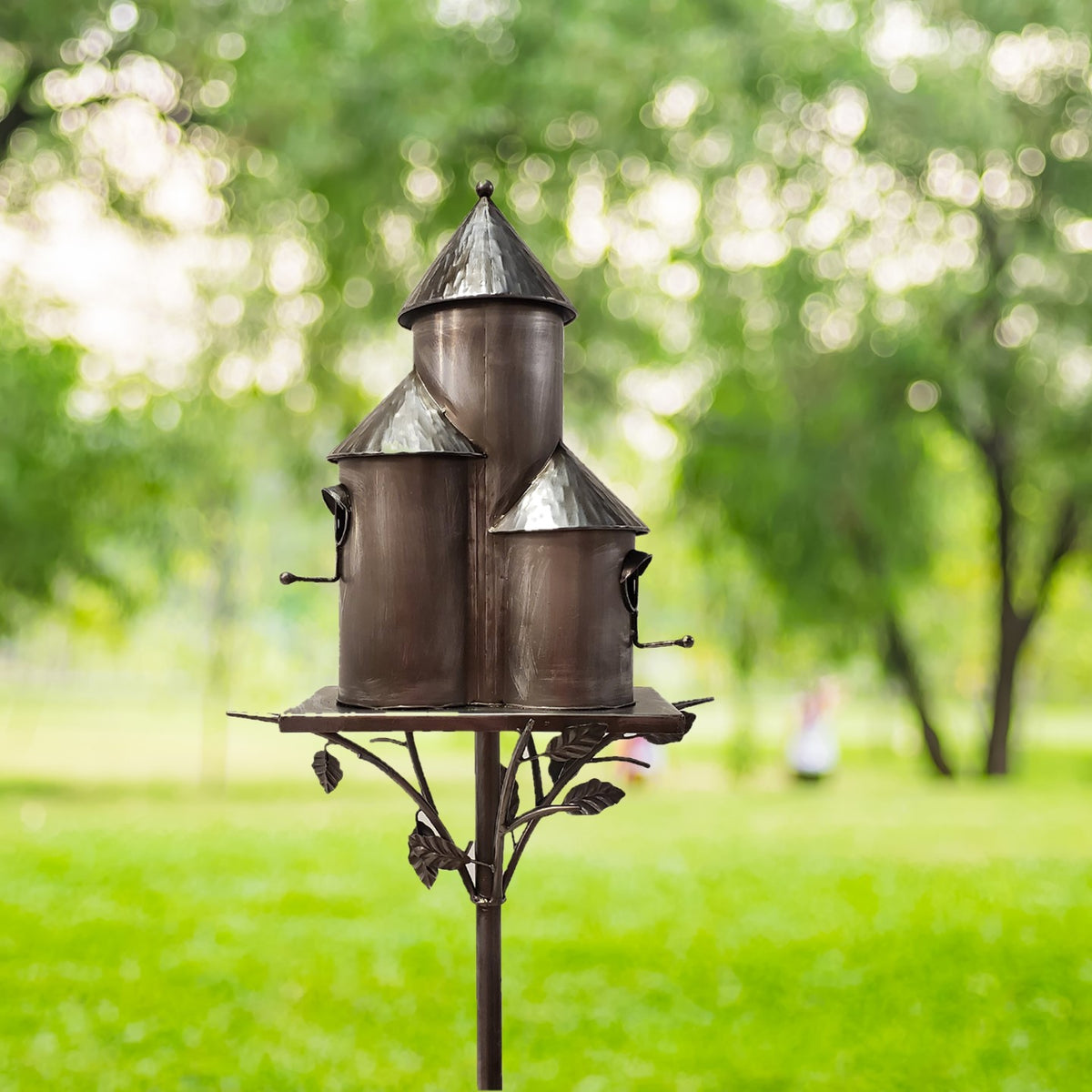 Decorative birdhouse on a stand with a blurred green garden background
