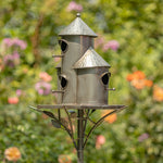 Metal birdhouse with multiple compartments on a stand against a blurred garden background