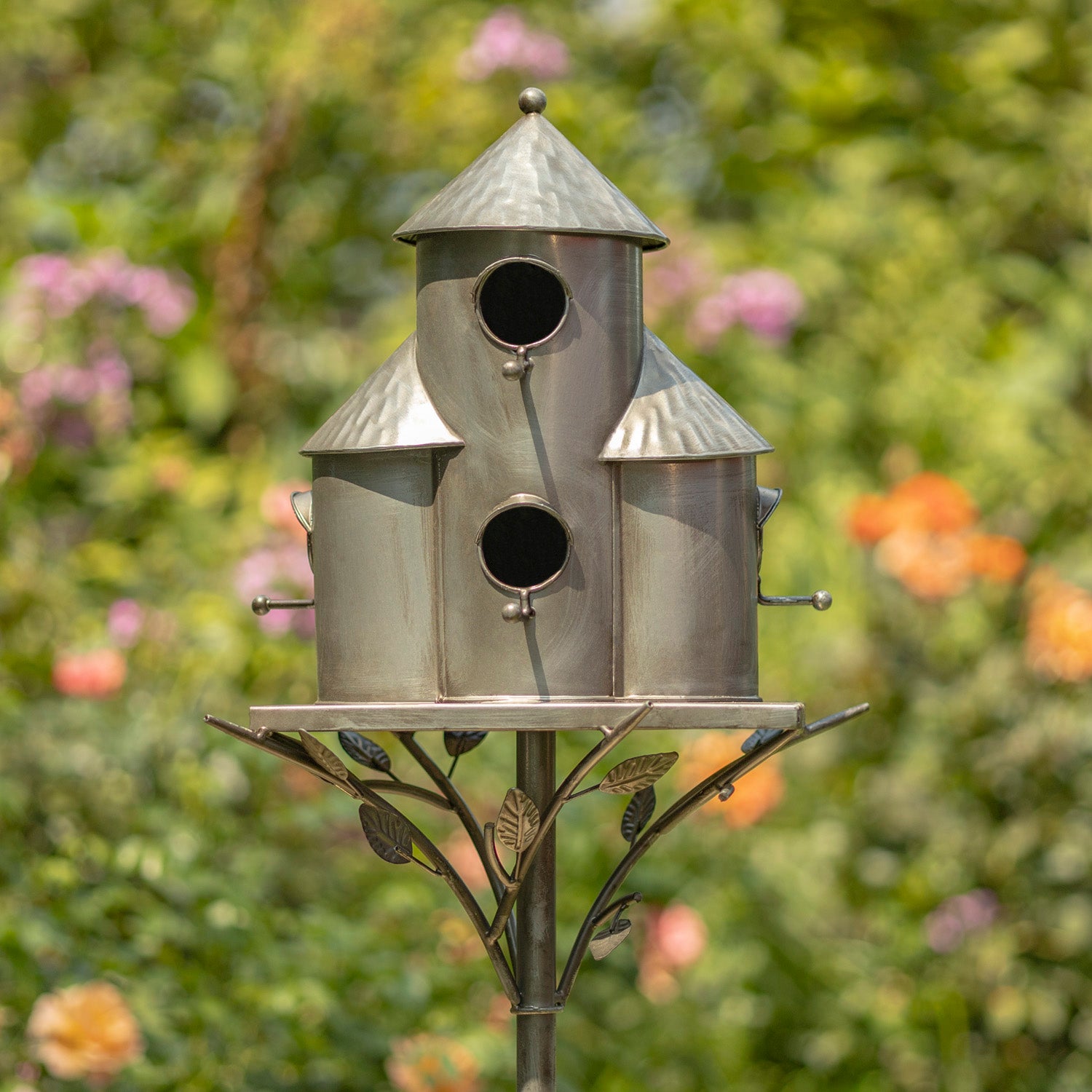 Metal birdhouse on a stand with a garden background