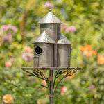 Metal birdhouse with a decorative stand against a blurred garden background