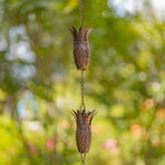 Decorative metal hanging planters with a chain against a blurred green background