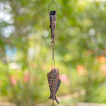Decorative wind chime with fish design against a blurred natural background