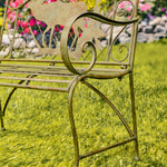 Rustic metal bench in a garden setting with blurred flowers and stones in the background