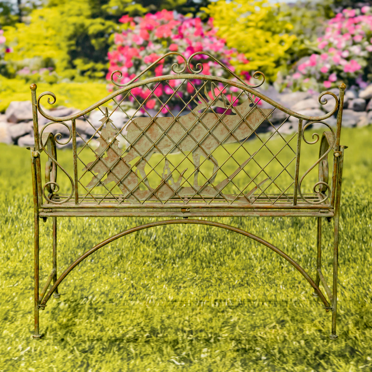 Decorative metal bench in a garden setting with flowers and rocks in the background