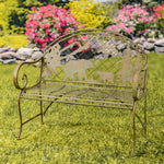 Decorative garden bench with bear design in a grassy area with flowers