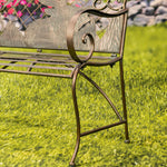 Decorative metal bench with intricate designs on a grassy background