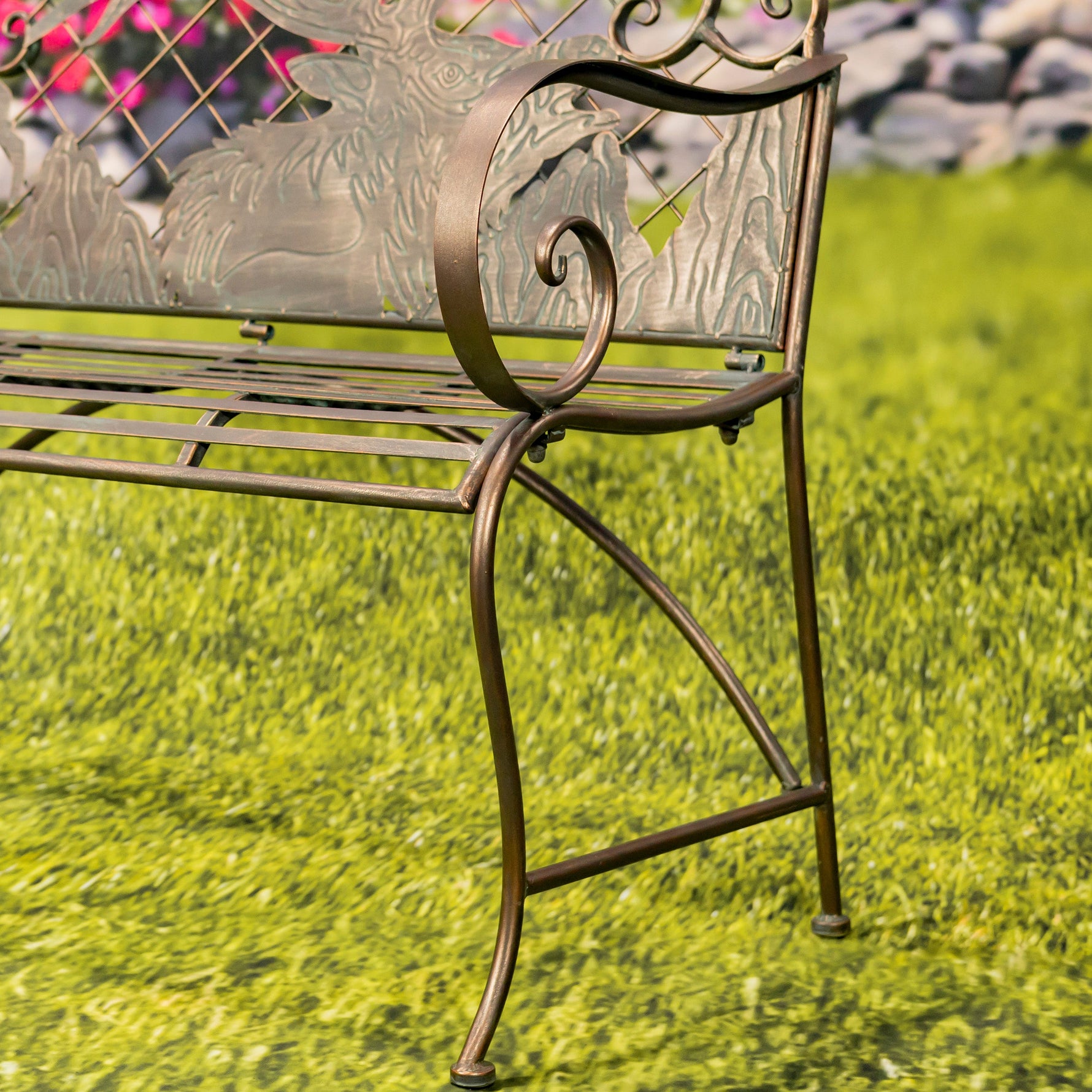Decorative metal bench with intricate designs on a grassy background
