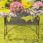 Decorative metal bench with leaf design in a garden setting