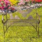 Decorative metal bench with bird design on a grassy area with flowers in the background