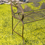 Decorative metal bench with nature-themed design on a grassy background
