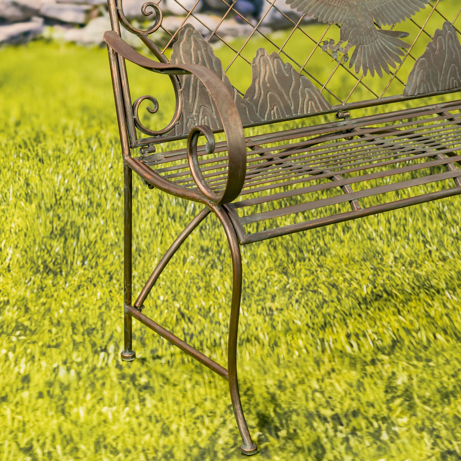 Decorative metal bench with nature-themed design on a grassy background