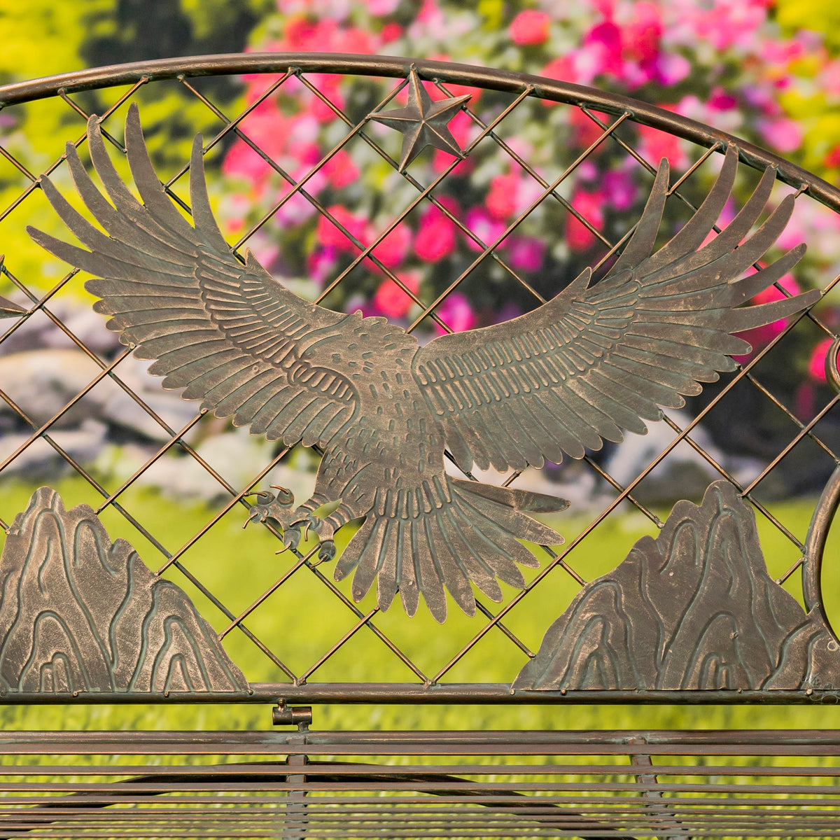 Metallic eagle sculpture on a decorative metal gate with blurred floral background