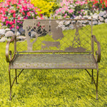 Decorative metal bench with cut-out designs on a grassy area with flowers in the background