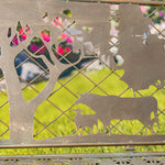Decorative metal fence with cut-out animal shapes and a tree, blurred background