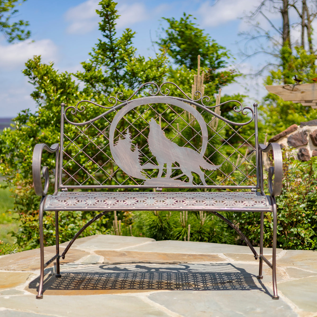 Decorative metal bench with wolf design in a garden setting