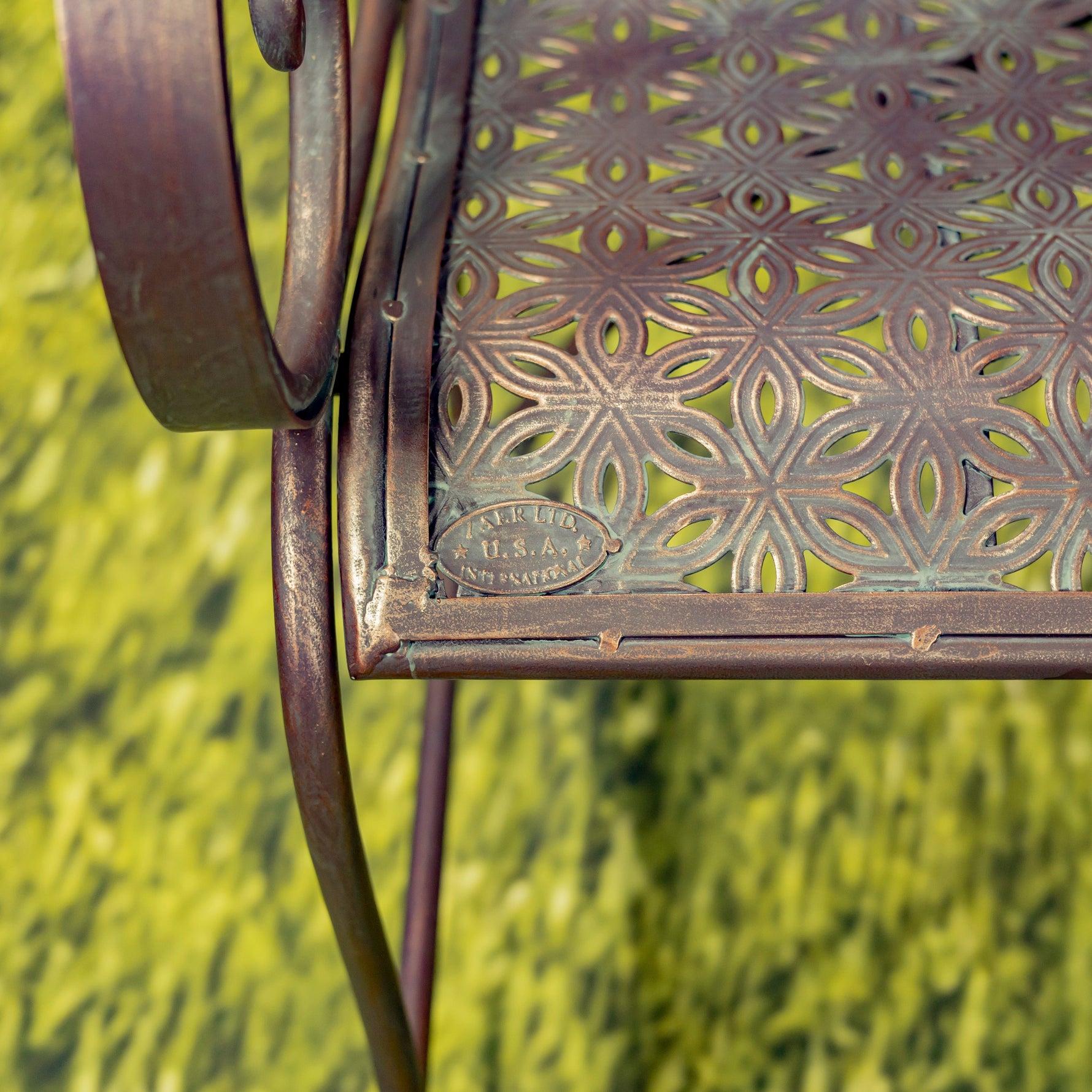 Decorative metal chair with intricate patterns on a grassy background