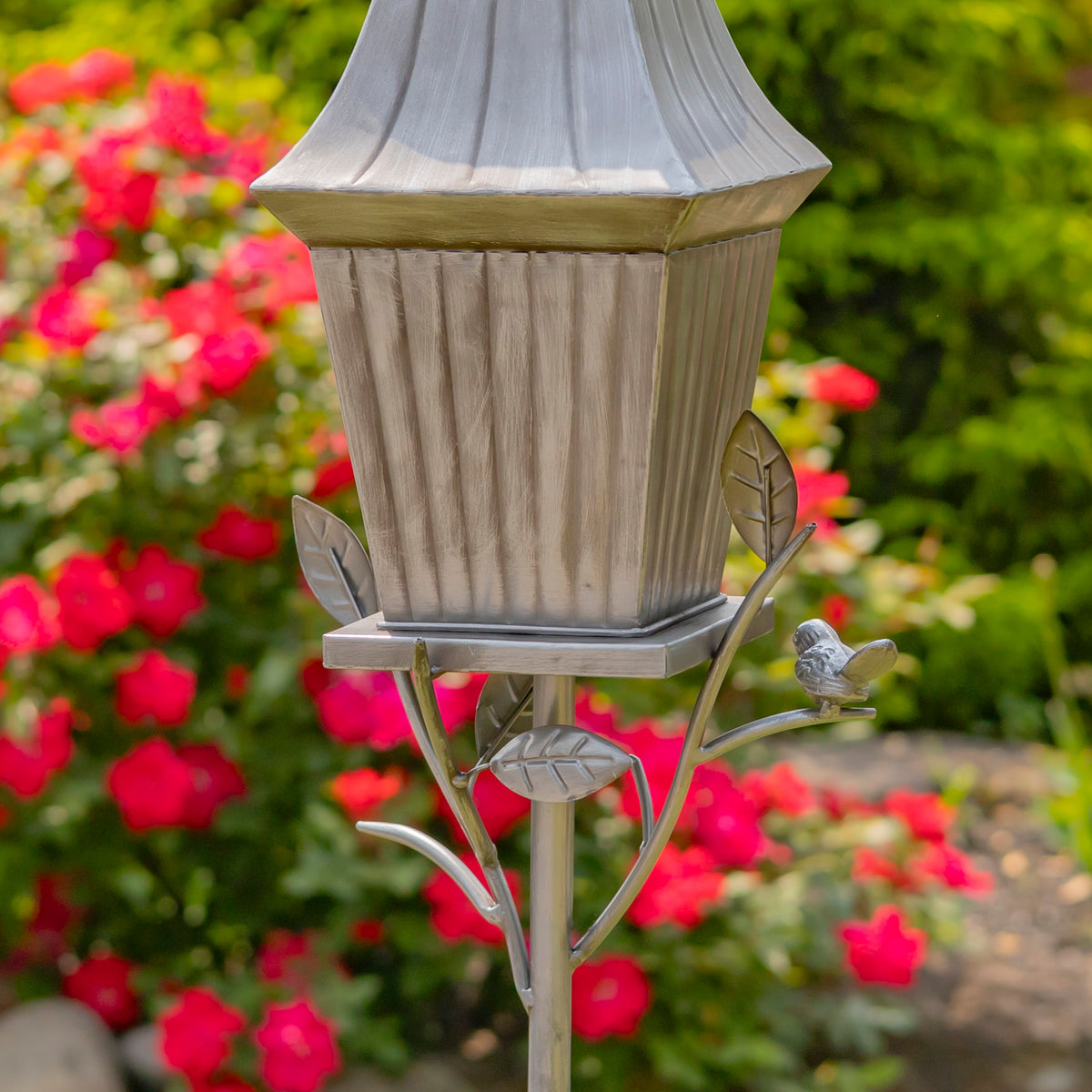 Decorative garden light fixture with bird design against a floral background