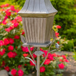Decorative garden light fixture with bird design against a floral background