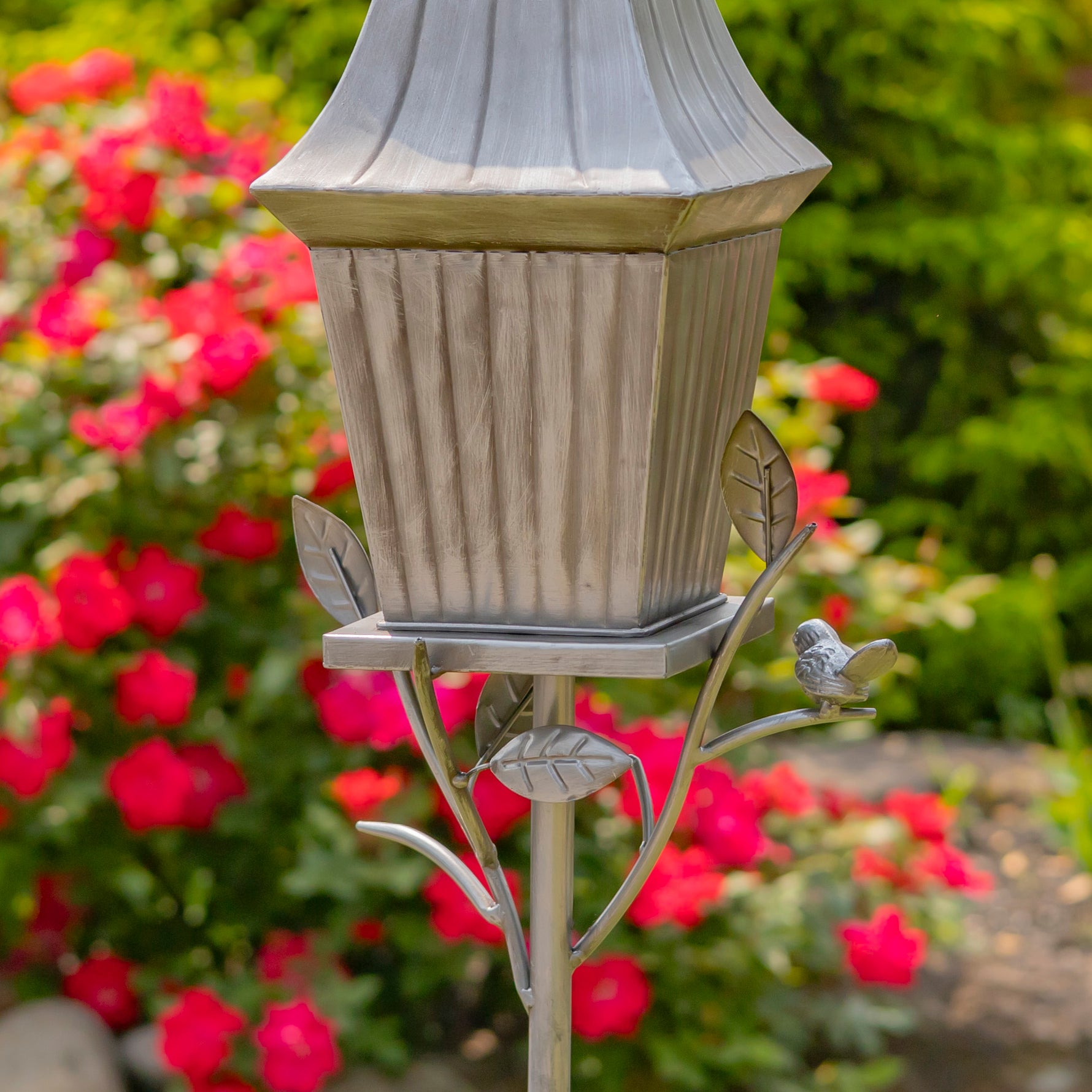 Decorative garden light fixture with bird design against a floral background