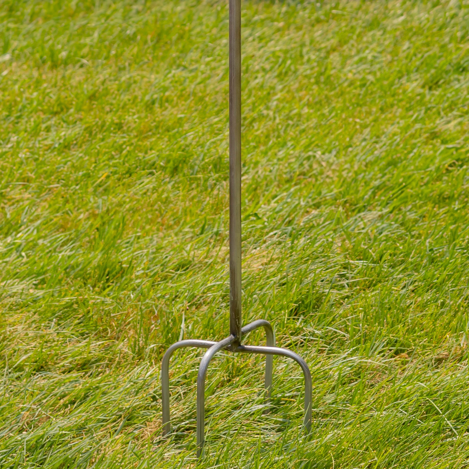 Metal garden fork on a grassy background