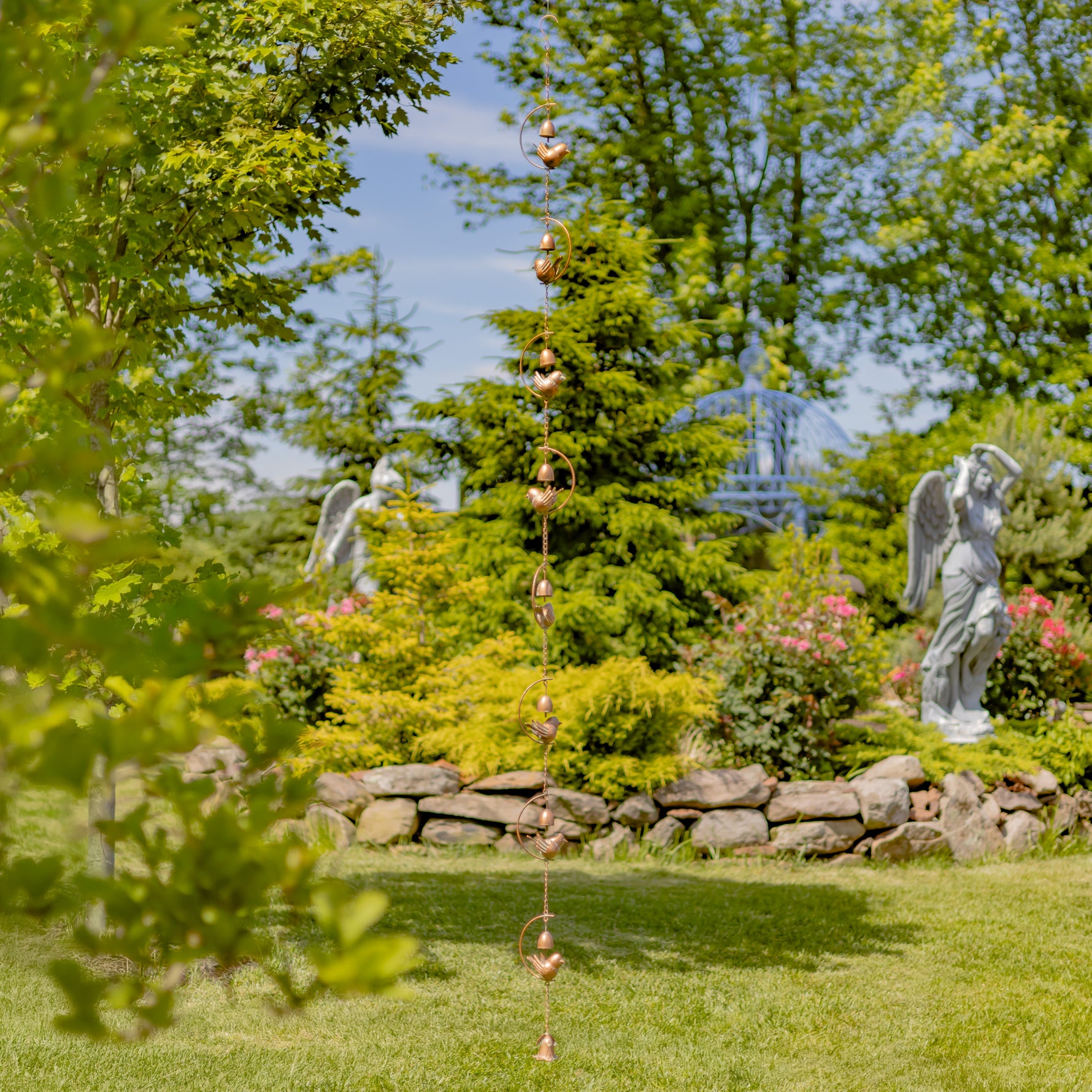 Decorative rain chain with angel statues in a garden setting