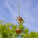 Decorative wind chime with a blue sky and green trees in the background