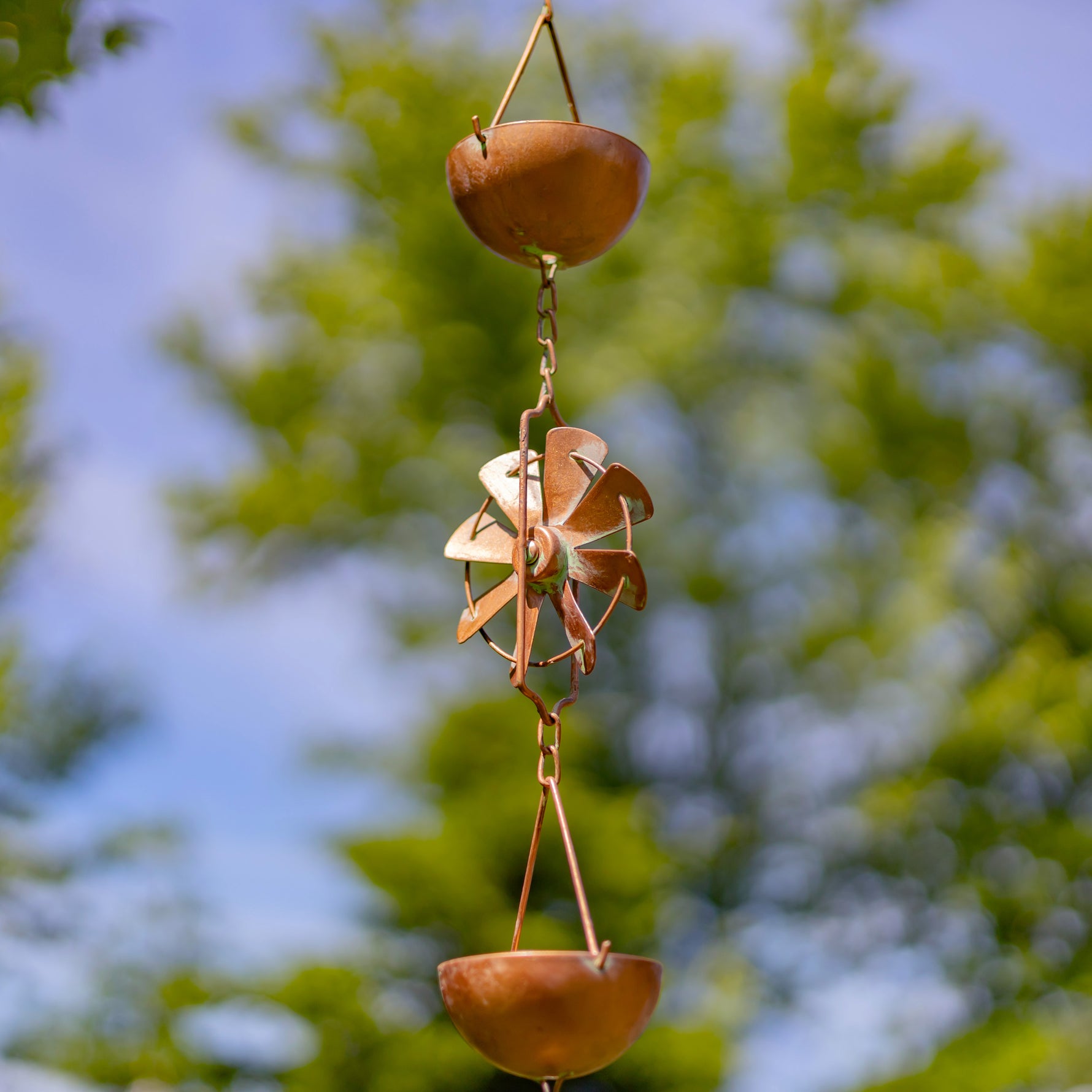 Decorative wind chime with hanging objects against a blurred natural background