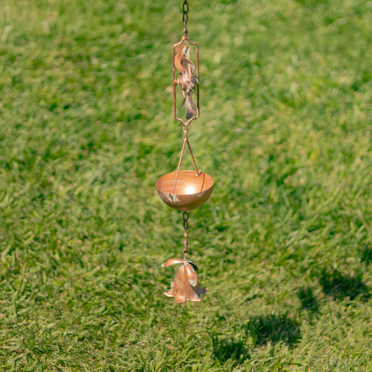 Copper wind chime hanging on a grassy background