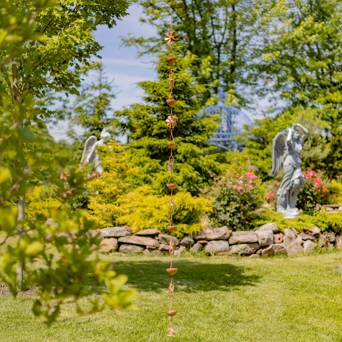 Decorative garden with angel statues, a stone wall, and a rain chain.