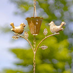 Decorative gold bird feeder with birds on a branch against a blurred green background