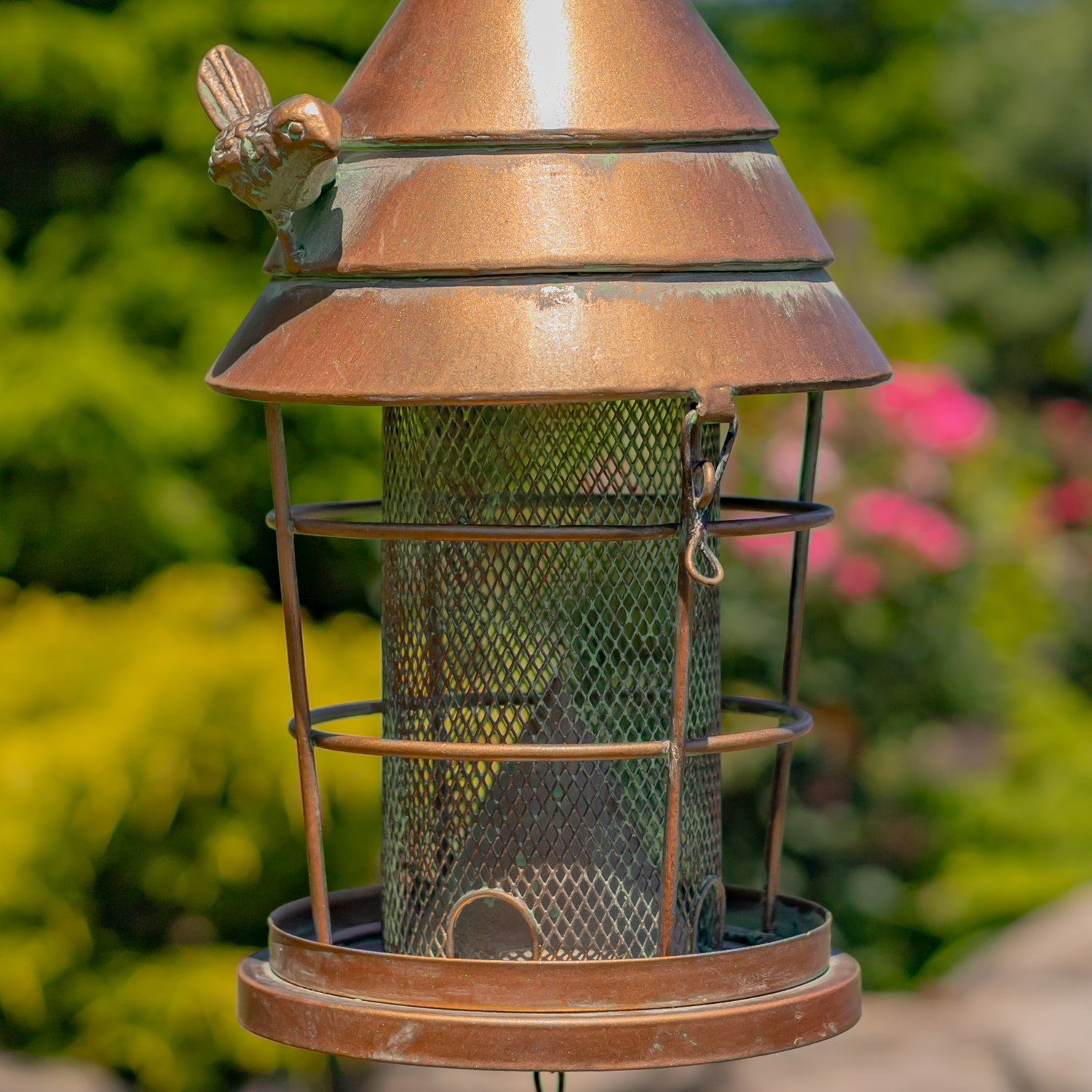 Bronze bird feeder with mesh side on a blurred garden background