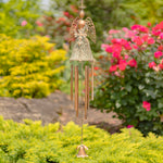 Decorative angel wind chime in a garden setting with flowers and greenery.