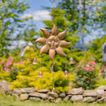 Decorative sun-shaped wind chime with hanging bells in a garden setting