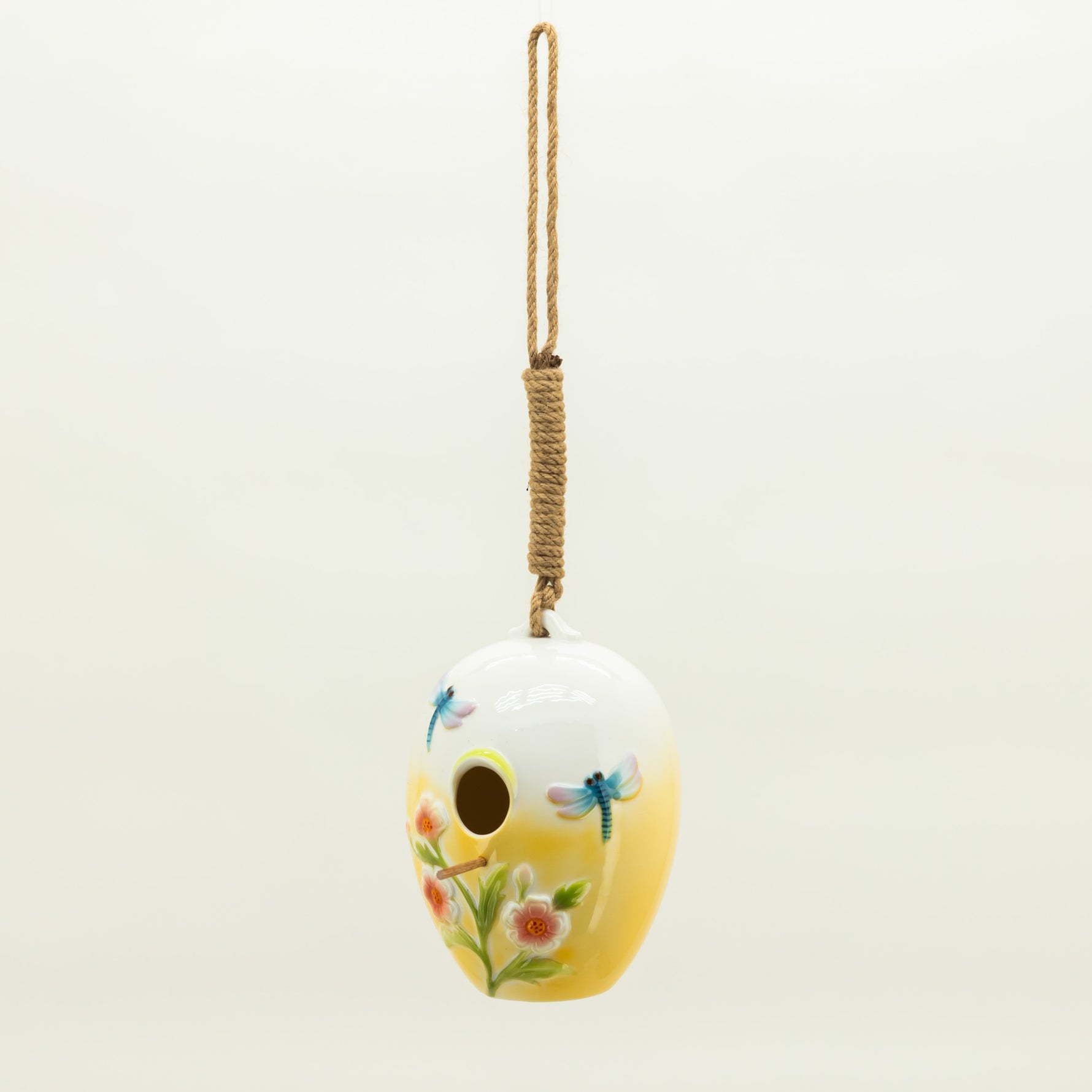 Decorative birdhouse with floral and dragonfly design on a white background