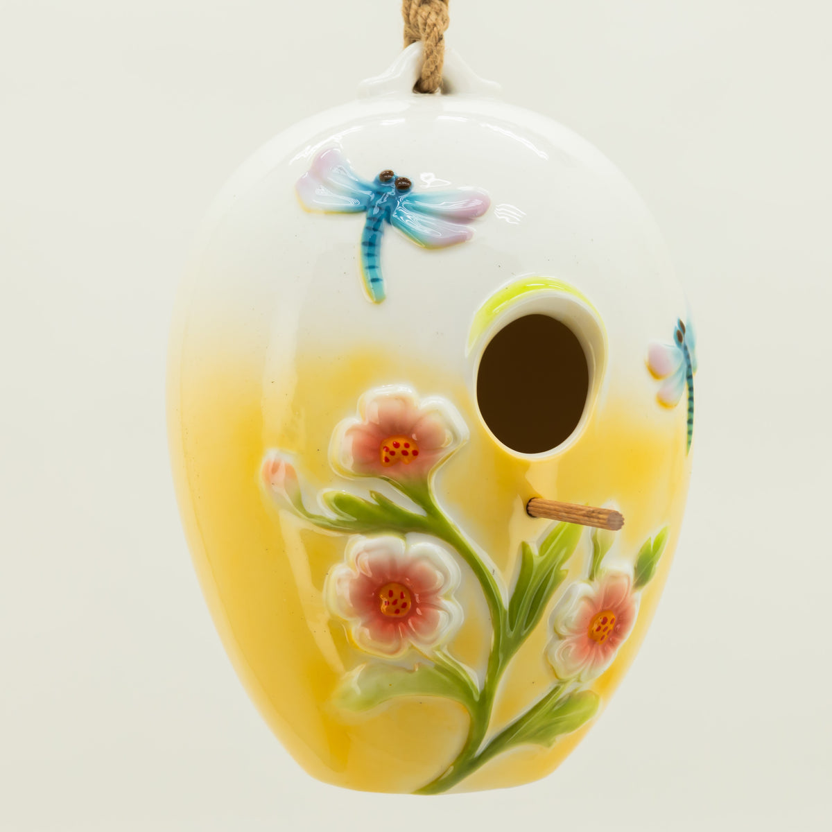 Decorative ceramic birdhouse with floral and dragonfly design on a white background