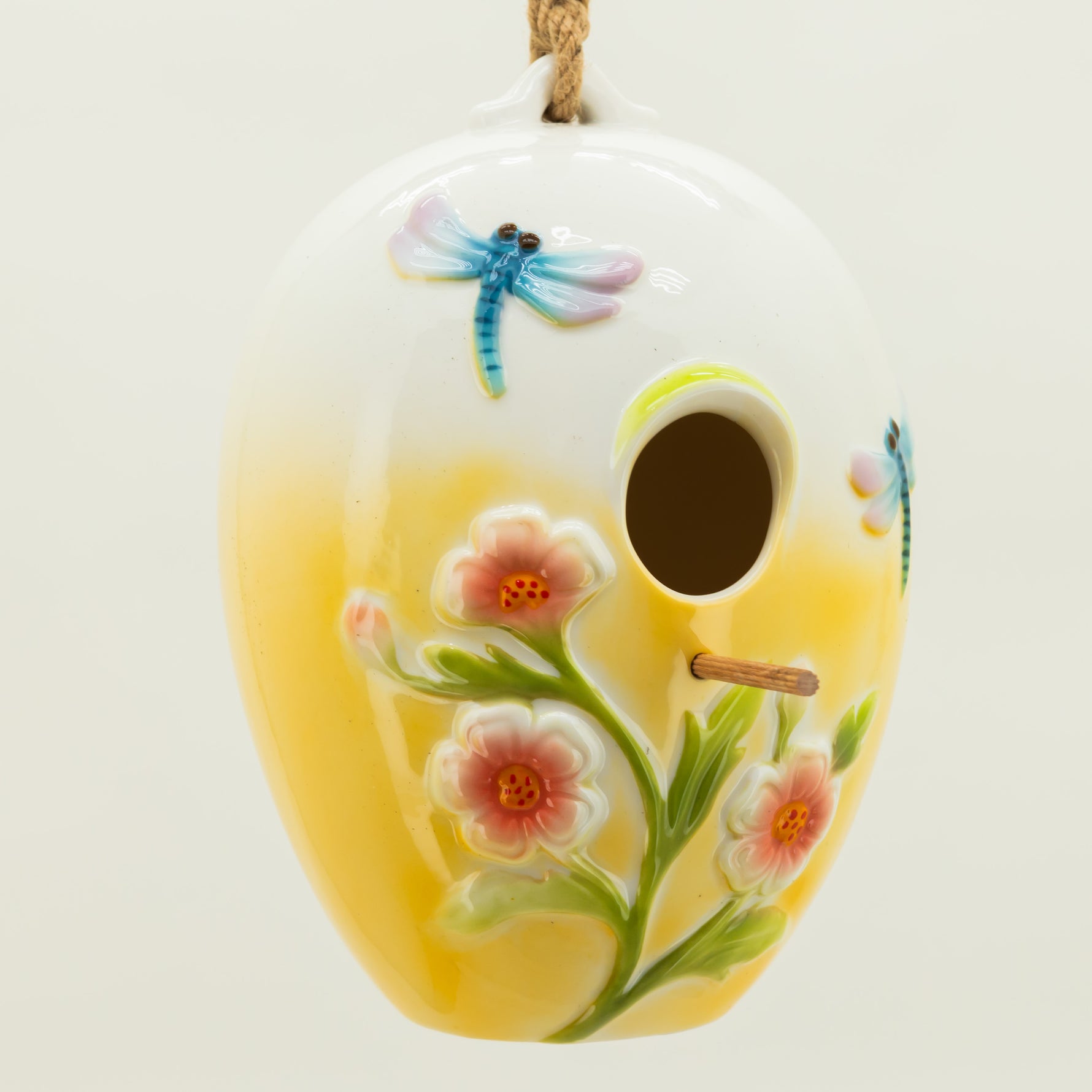 Decorative ceramic birdhouse with floral and dragonfly design on a white background