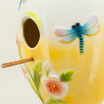 Decorative ceramic birdhouse with floral and dragonfly designs on a white background