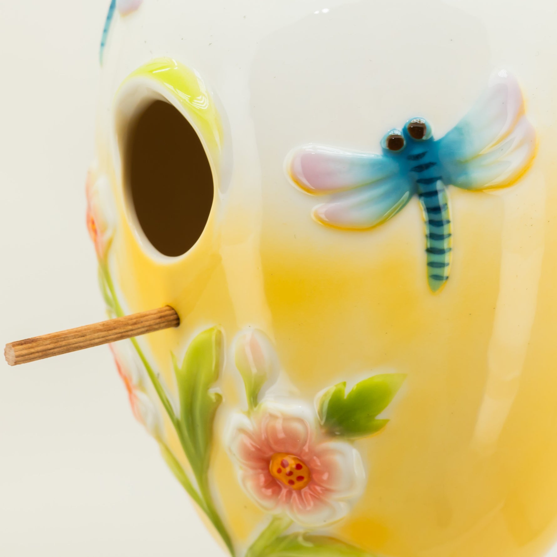 Decorative ceramic birdhouse with floral and dragonfly designs on a white background