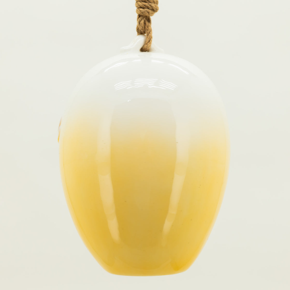 Yellow glass vase with a white top on a light gray background