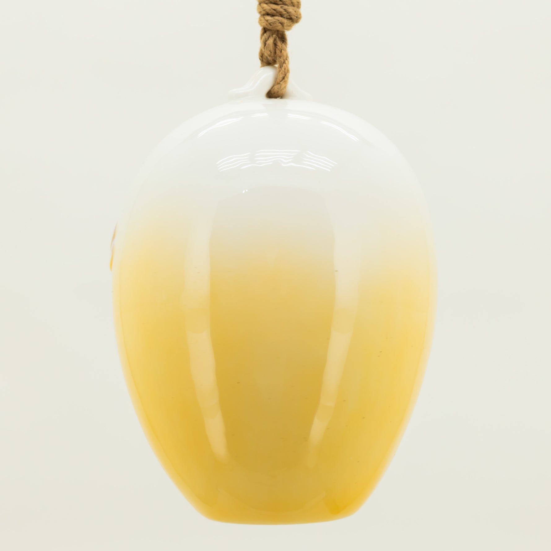 Yellow glass vase with a white top on a light gray background