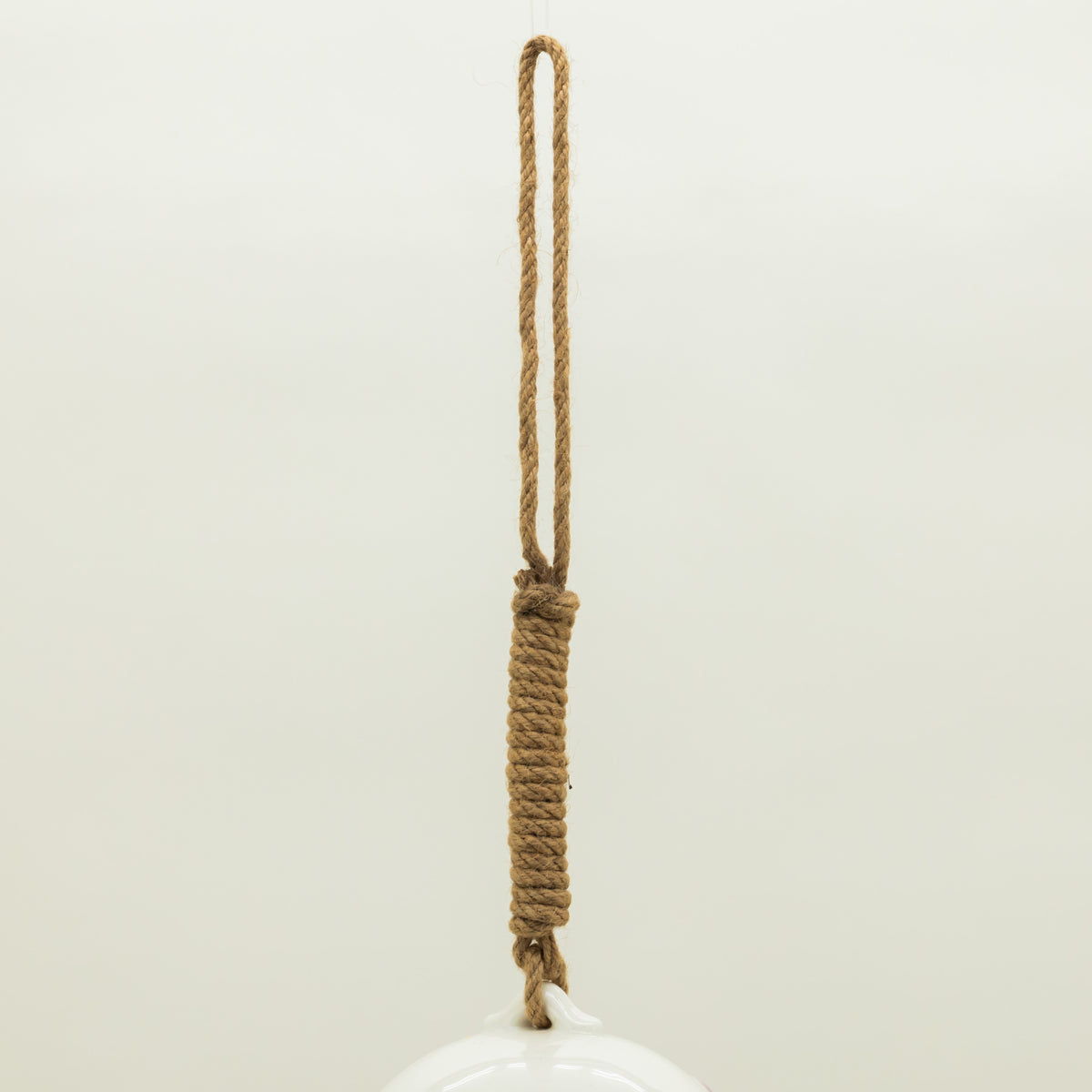 White ceramic object with a rope handle on a light beige background