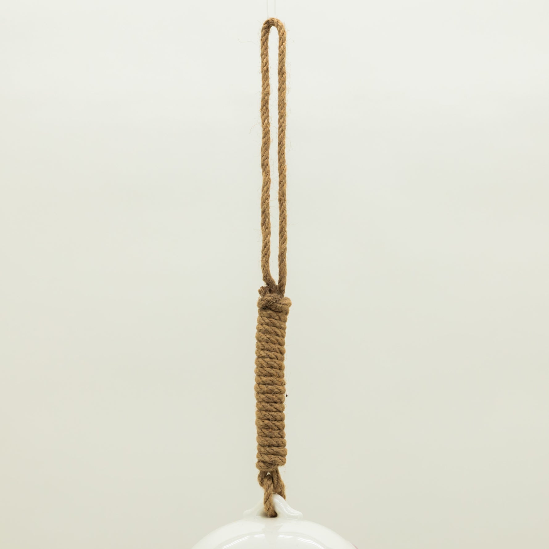 White ceramic object with a rope handle on a light beige background