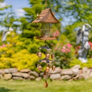 Birdfeeder and windchime hanging on green tree with lovely garden background