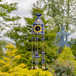 Decorative wind chime with sunflower design against a blurred garden background